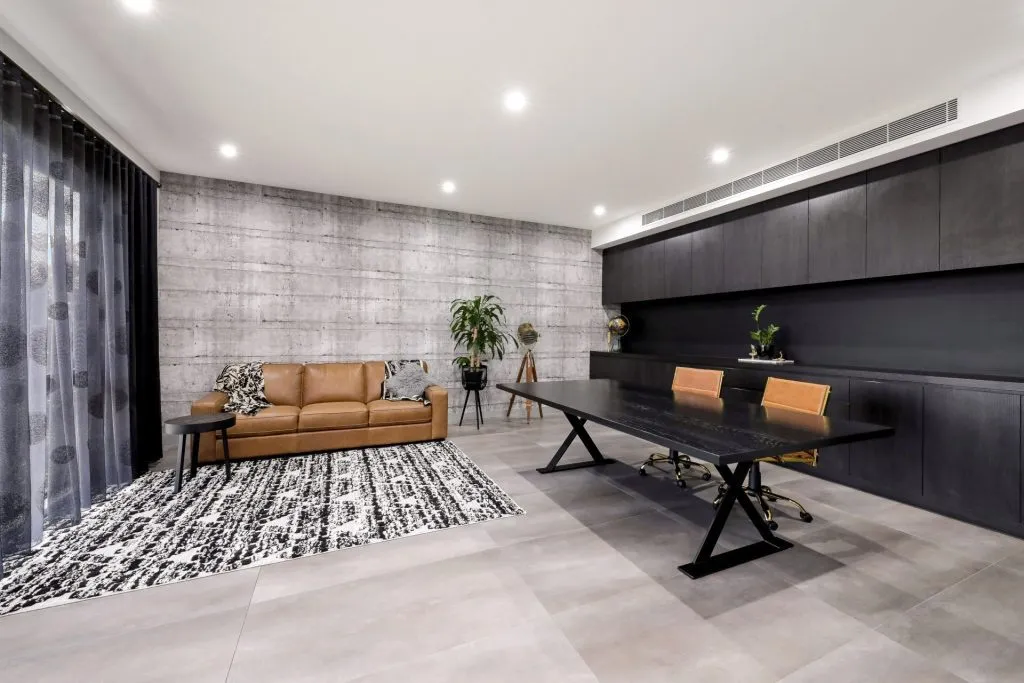 Modern home office with brown couch, large desk, and stylish decor.
