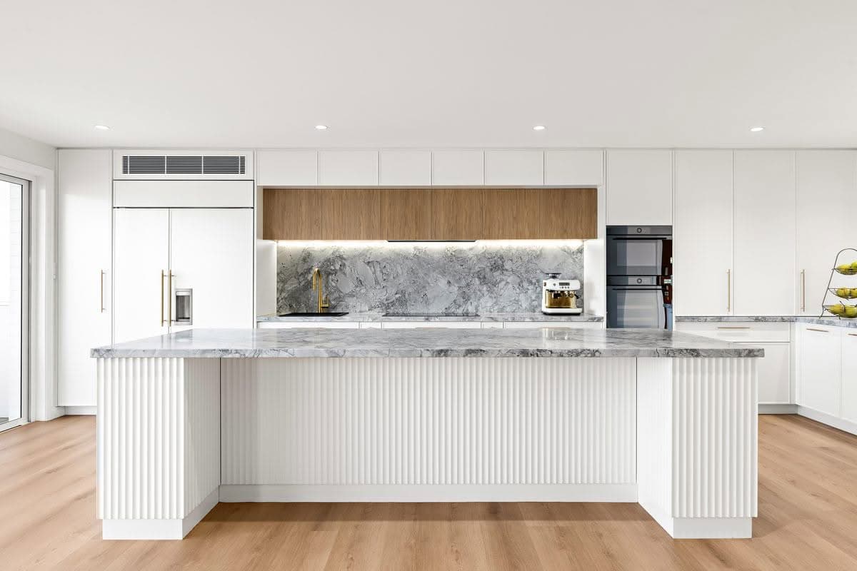 Open-plan kitchen renovation with fluted island and marble splas