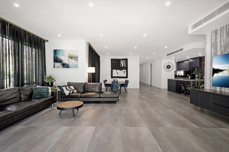 Experience the pinnacle of modern living with this exquisite open-plan living room renovation by Dura Group. As a Sydney-based, family-owned building company, Dura Group specializes in transforming living spaces across the Sutherland Shire, Bayside, Inner West, Georges River, and Randwick regions. This luxurious living area features a seamless blend of contemporary design and functional elegance, boasting premium leather sofas, stylish artwork, and sophisticated lighting fixtures. The chic dining area and state-of-the-art kitchen reflect our commitment to quality and detail. Led by Managing Director Mark, who brings over 27 years of construction experience, Dura Group prioritizes time efficiency, budget-conscious planning, and consistent communication to ensure your renovation journey is smooth and satisfying. Our homeowner-first approach focuses on trust, transparency, and tailored solutions. Transform your space with Dura Group and enjoy a stylish, modern home that perfectly suits your lifestyle. Embark on your renovation journey with us today and elevate your living experience. Contact Dura Group now to start planning your dream home transformation!