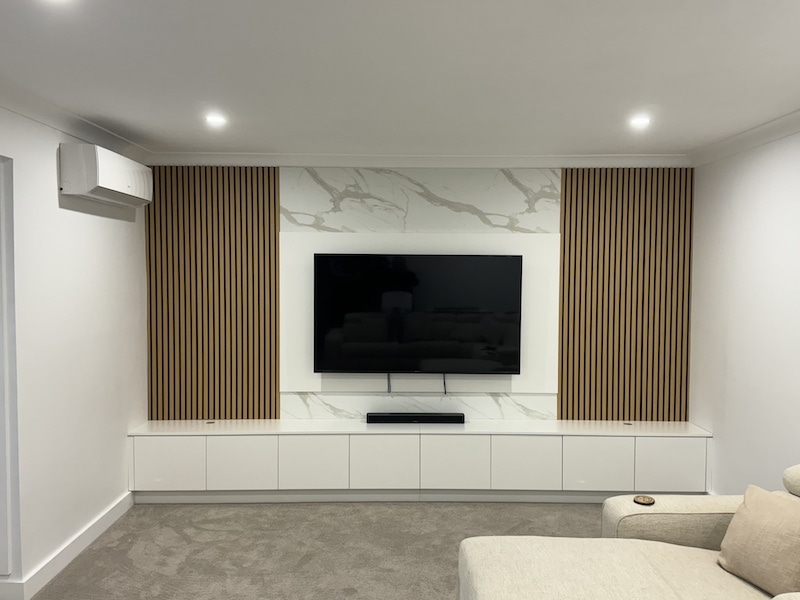 Discover the elegance of a modern home theatre setup by Dura Group, a leading Sydney-based family-owned building company specializing in customized renovations. This stylish design features a state-of-the-art television mounted against a sophisticated backdrop of marble and wooden panels, offering a perfect blend of aesthetics and functionality. Dura Group, led by Managing Director Mark with over 27 years of experience, excels in creating personalized home environments across the Sutherland Shire, Bayside, Inner West, Georges River, and Randwick regions. Our expertise in home renovations, ground floor extensions, upper storey additions, kitchen upgrades, bathroom remodels, and laundry renovations ensures top-notch outcomes tailored to your needs. Prioritizing time efficiency, budget-conscious planning, and transparent communication, Dura Group guarantees home improvement ideas without compromising on build quality. Transform your living room into a high-end entertainment hub and enjoy an exceptional viewing experience at home. Contact us today for a consultation, and let’s bring your dream home vision to life with Dura Group’s homeowner-first focus on trust and transparency.