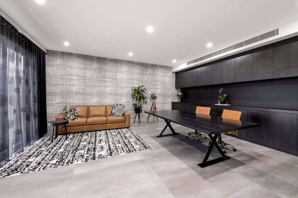 Modern home office with brown couch, large desk, and stylish decor.