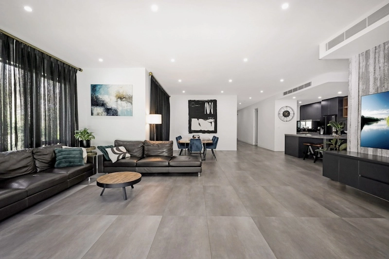 Experience the pinnacle of modern living with this exquisite open-plan living room renovation by Dura Group. As a Sydney-based, family-owned building company, Dura Group specializes in transforming living spaces across the Sutherland Shire, Bayside, Inner West, Georges River, and Randwick regions. This luxurious living area features a seamless blend of contemporary design and functional elegance, boasting premium leather sofas, stylish artwork, and sophisticated lighting fixtures. The chic dining area and state-of-the-art kitchen reflect our commitment to quality and detail. Led by Managing Director Mark, who brings over 27 years of construction experience, Dura Group prioritizes time efficiency, budget-conscious planning, and consistent communication to ensure your renovation journey is smooth and satisfying. Our homeowner-first approach focuses on trust, transparency, and tailored solutions. Transform your space with Dura Group and enjoy a stylish, modern home that perfectly suits your lifestyle. Embark on your renovation journey with us today and elevate your living experience. Contact Dura Group now to start planning your dream home transformation!