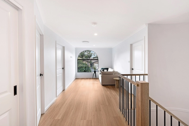 Discover the elegance of an upper storey addition crafted by Dura Group. This spacious, light-filled area features a sleek hallway with pristine white doors and a large, arched window that offers a scenic view. A comfortable sofa and stylish side table enhance the welcoming atmosphere. With over 27 years of construction experience, Dura Group specializes in home renovations and additions across Sydney. We prioritize time efficiency and budget-conscious planning without compromising on quality. Our family-owned company, led by Managing Director Mark, focuses on trust, transparency, and tailored building solutions. Experience seamless communication and a homeowner-first approach in every project. Whether you’re considering a renovation or new addition, trust Dura Group to bring your vision to life. Contact us today to start your renovation journey and transform your living space with expert craftsmanship.