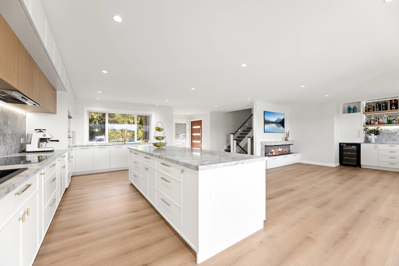 Experience the elegance and functionality of modern living with Dura Group's exquisite kitchen renovation. Our Sydney-based, family-owned building company transforms outdated spaces into luxurious culinary havens. This expansive kitchen, nestled across the Sutherland Shire and surrounding regions, features sleek, white cabinetry complemented by high-quality marble countertops, offering both style and durability. The open layout enhances natural light, creating a welcoming environment for family gatherings. Dura Group prioritizes time efficiency, ensuring projects meet deadlines without compromising on quality. With over 27 years of construction experience, our Managing Director, Mark, leads a team devoted to precision and creativity. We focus on trust, transparency, and homeowner-first approaches, tailoring solutions to fit your unique needs. Whether you're planning a ground floor extension, upper storey addition, or a complete home renovation, Dura Group's expertise in kitchen upgrades and other remodeling projects guarantees satisfaction. Let us elevate your home, enhance your lifestyle, and bring your vision to life. Contact Dura Group today and discover how our tailored building solutions can transform your home into a masterpiece. Embrace elegant designs and quality craftsmanship tailored to your budget and style.