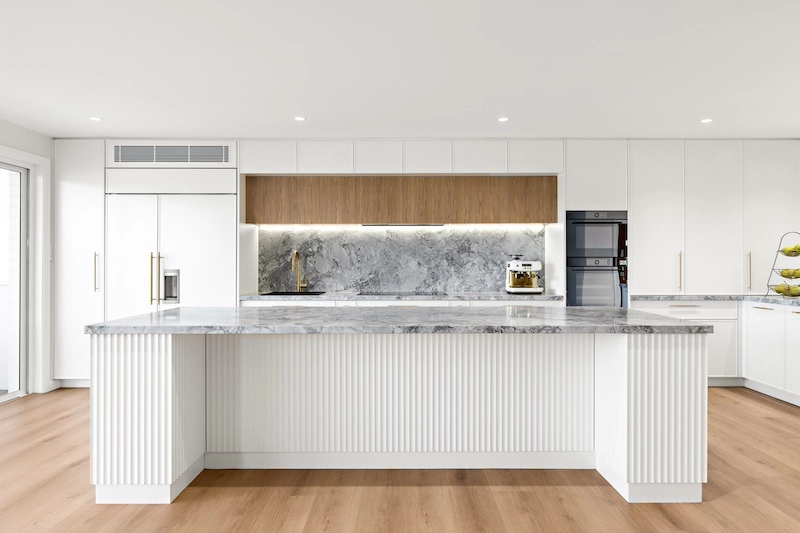 Transform your home with a luxury kitchen renovation by Dura Group, a trusted Sydney-based family-owned building company. Our expertise in home renovations shines through in this modern kitchen design featuring exquisite marble countertops, sleek cabinetry, and state-of-the-art appliances. With over 27 years of construction experience, Dura Group delivers time-efficient and budget-conscious projects across Sutherland Shire, Bayside, Inner West, Georges River, and Randwick. Our focus on trust and transparency ensures a seamless renovation experience, prioritizing quality and homeowner satisfaction. Upgrade your kitchen with a bespoke touch and enhance the heart of your home. Experience our tailored building solutions with a stress-free consultation. Discover the difference with Dura Group today and see how we can transform your living space into a masterpiece. Contact us for more details and start your renovation journey now!