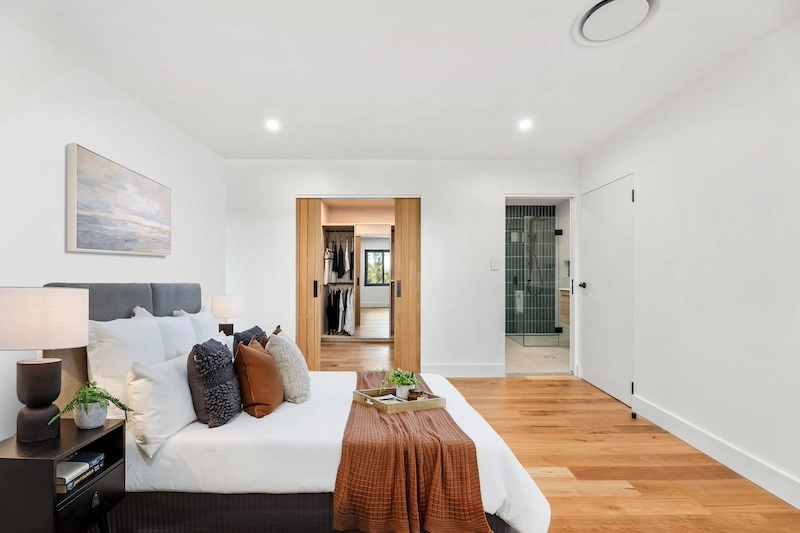 Discover the epitome of luxurious living with this beautifully designed master bedroom featuring an adjoining ensuite, crafted by Dura Group. As specialists in home renovations across Sydney, Dura Group brings over 27 years of expertise, ensuring impeccable build quality and homeowner-first service. This master suite showcases our commitment to creating tailored building solutions that reflect comfort and style. The room features a sophisticated color palette, plush bedding, and practical, elegant furnishings. The ensuite offers modern fixtures and a sleek design that promises both functionality and aesthetic appeal. With our focus on transparent communication, budget-conscious planning, and timely project delivery, Dura Group transforms your living spaces into dream havens. Experience the difference with our ground floor extensions, upper storey additions, kitchen upgrades, and bathroom and laundry renovations that breathe new life into your home. Let us partner with you in crafting spaces that enhance your lifestyle. Contact us today for a consultation and start your journey to enriched living with Dura Group. Act now; your dream home is just a call away!