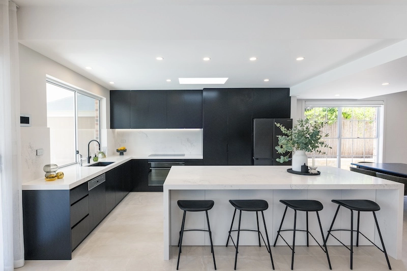 Discover a stunning kitchen renovation by Dura Group, a family-owned building company in Sydney, renowned for their excellence in home renovations. This beautifully designed kitchen features sleek black cabinetry, a spacious marble island, and contemporary seating, perfect for both cooking and entertaining. With over 27 years of construction experience, Dura Group ensures top-notch quality and timely delivery in the Sutherland Shire, Bayside, Inner West, Georges River, and Randwick regions. Specializing in kitchen upgrades, home renovations, and more, they prioritize trust, transparency, and homeowner satisfaction. Transform your kitchen into a modern masterpiece with Dura Group's expert craftsmanship. Contact us today to start your renovation journey and bring your vision to life.